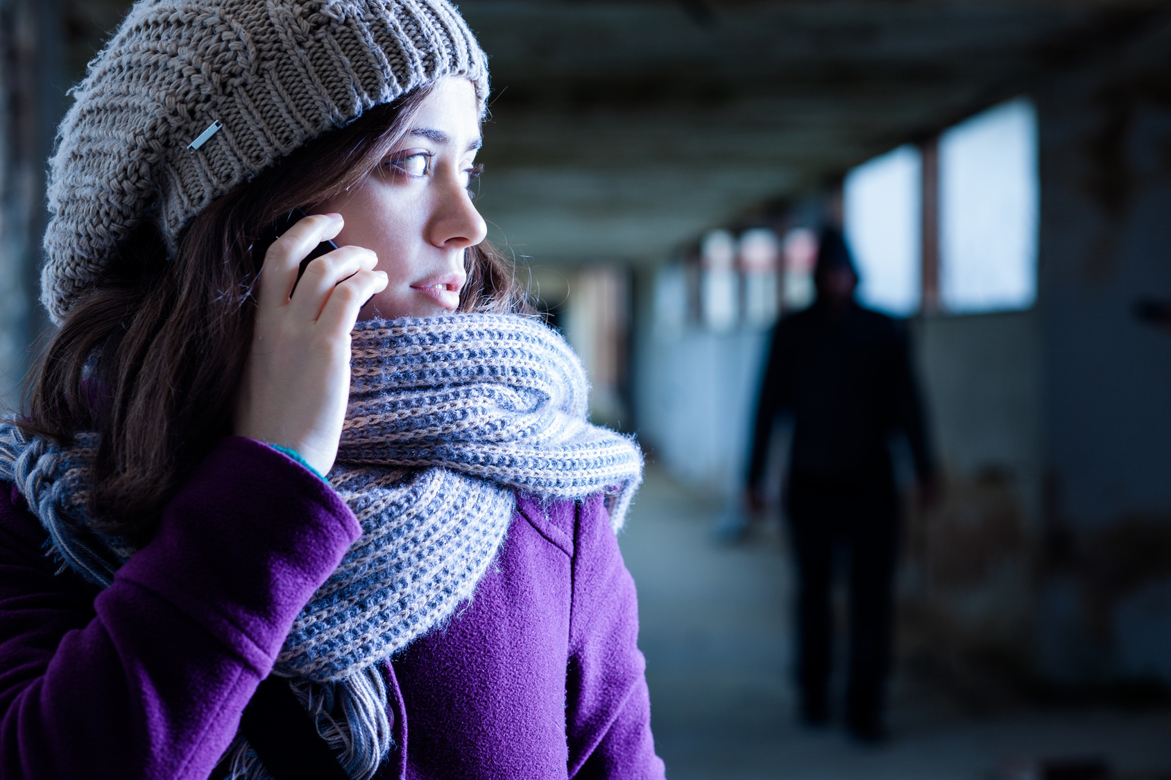 Junge Frau mit Handy, im Hintergrund ein Verfolger im Schatten; Kurtz Detektei Hamburg, Detektiv in Hamburg, Privatermittler in Hamburg, Privatdetektiv in Hamburg